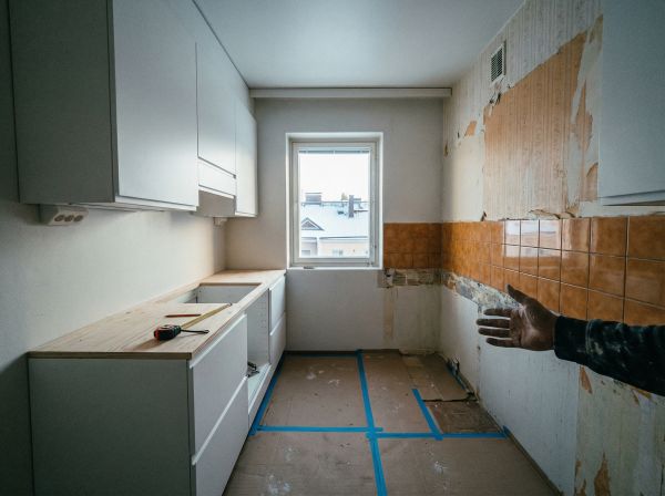 Laajakulvakuva 1970-luvun kerrostaloasunnon keittiöstä keskeneräisen remontin aikana, jossa näkyy uudet kaapit ja vanha kaakelointi
